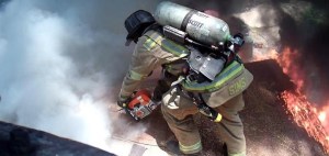 This is the type of dangerous work that Atlanta firefighters cite in their calls for a significant pay raise. Here, a firefigher uses a chainsaw to cut a vent hole in the roof of a structure fire this week along Donald Lee Hollowell Parkway. Credit: AFR Report
